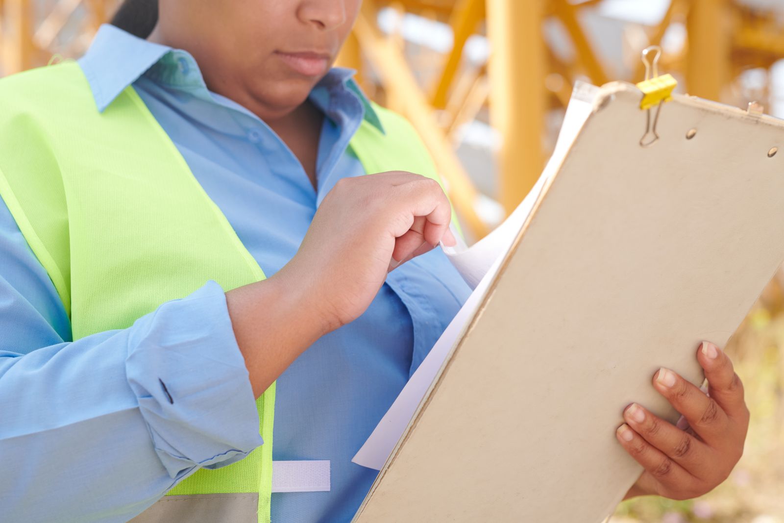 Engineer with safety gear reviewing a clipboard at a construction site, illustrative ISO 45001 auditing image